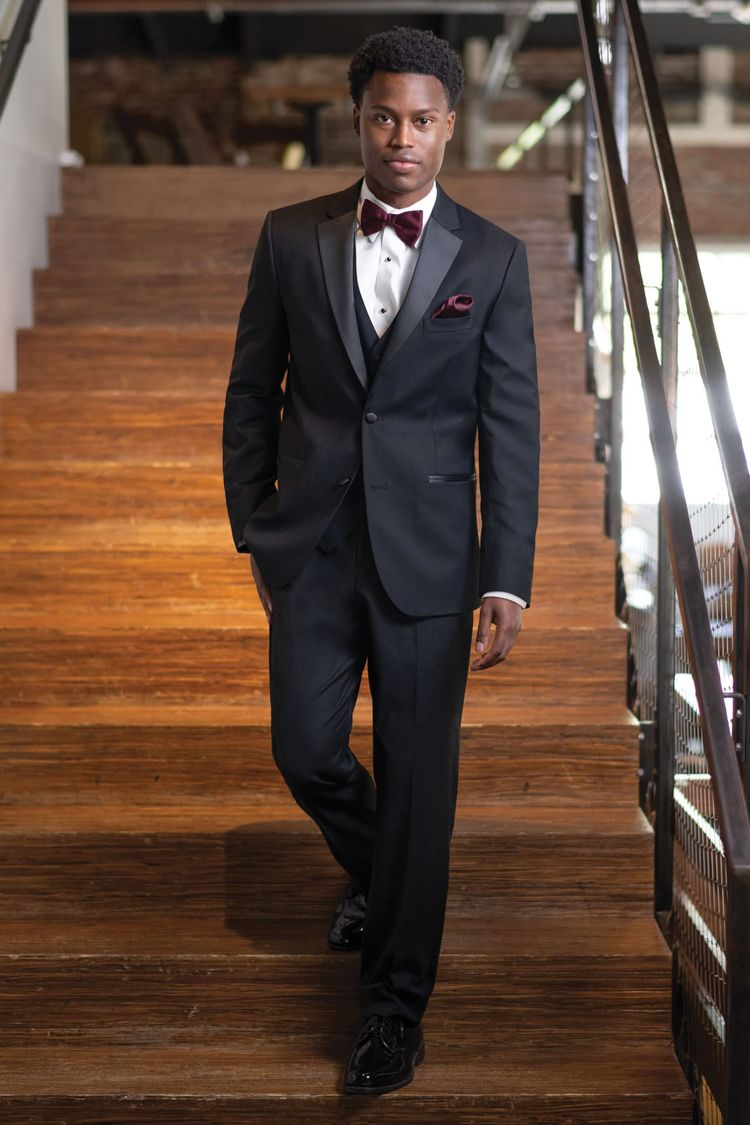 man wear black stretch tuxedo with matching pants, white dress shirt, black cufflinks and studs, and a wine colored bow tie.