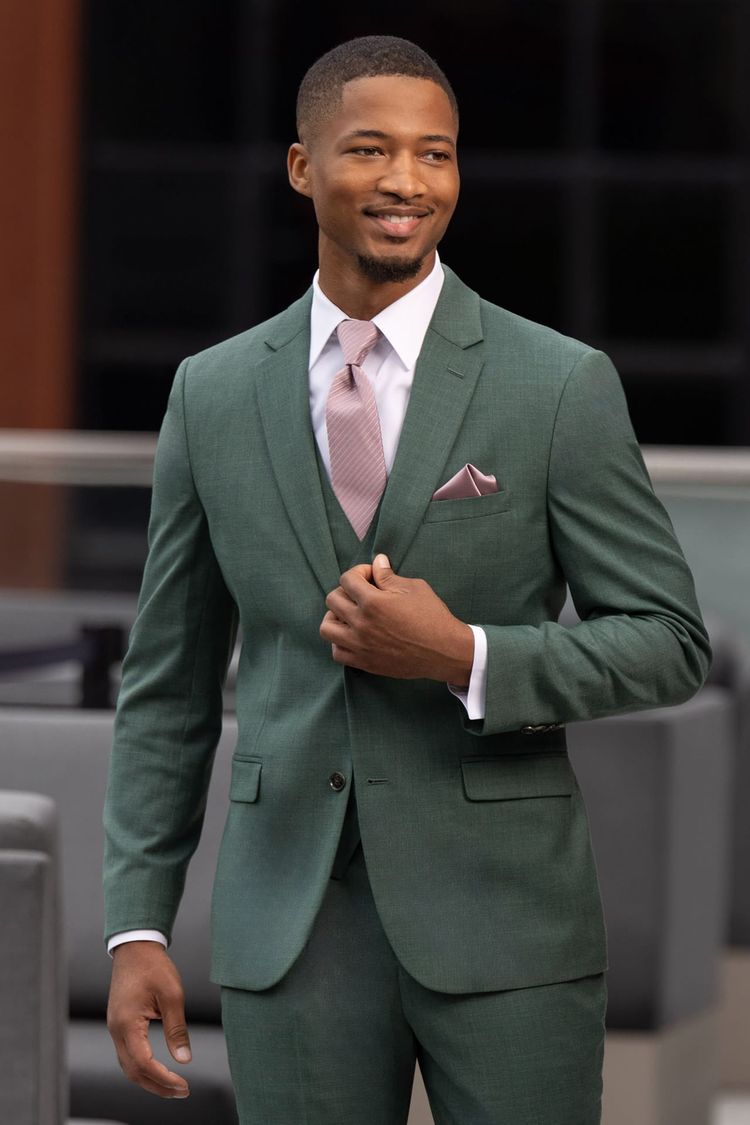 man wearing forest green stretch suit with matching vest, white shirt, and quartz striped windsor tie