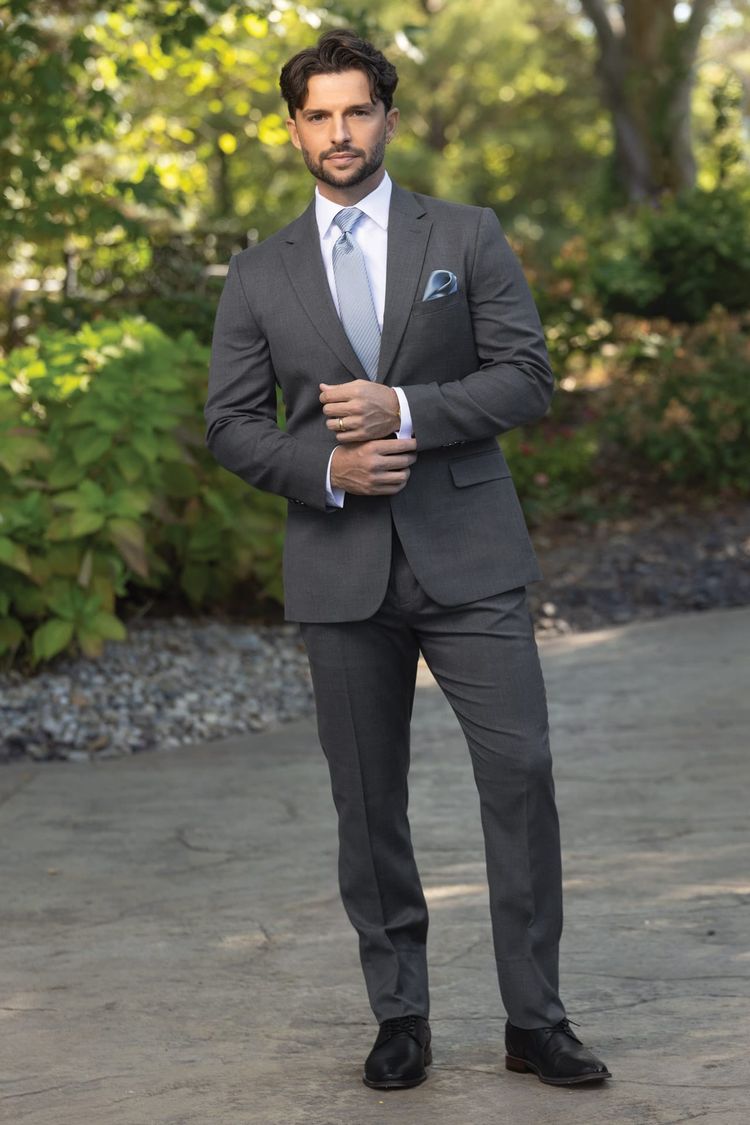 man wear a slate grey suit coat, pant and vest with a dusty blue windsor tie and pocket square